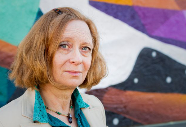 Christina framför väggmålning på Kulturskolans fasad.