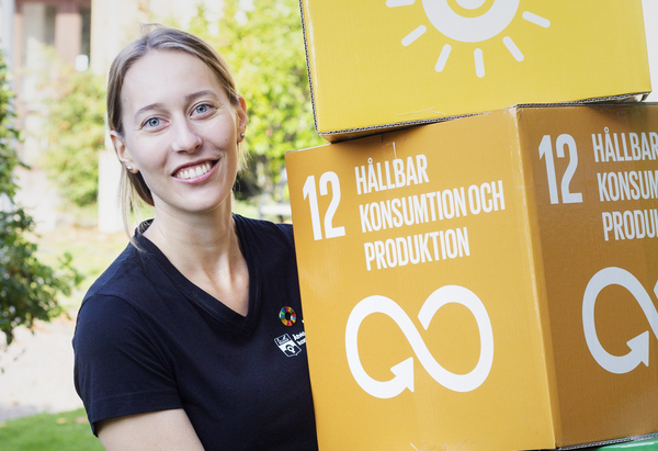 Klimatrådgivare Klara står med kartonger med information om Agenda 2030 på.