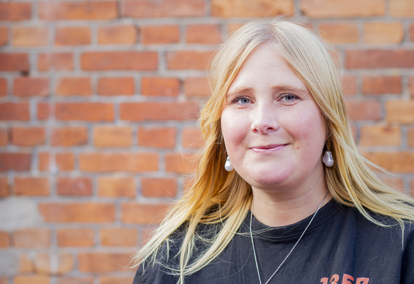 Kristin står framför en tegelvägg.