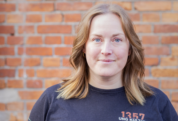 Caroline står framför en tegelvägg. 