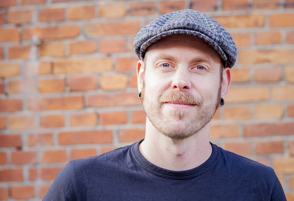 Johannes står framför en tegelvägg. 